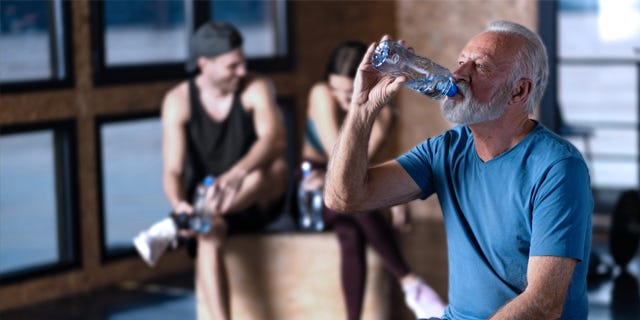 Man drinking water whilst exercising